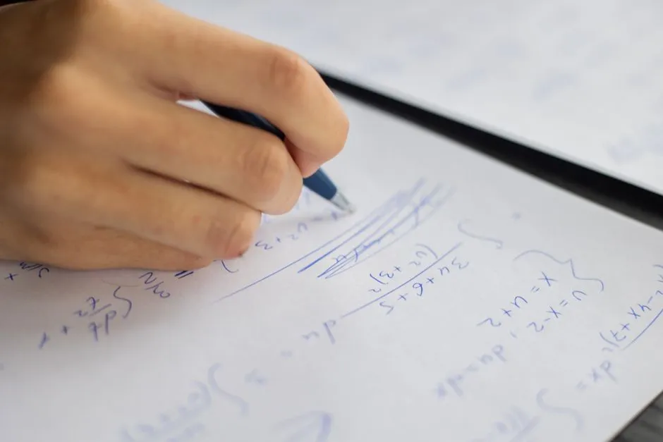 Printed Mathematics worksheet on a classroom desk beside sharpened pencils and an eraser